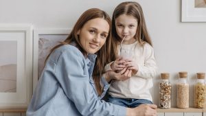 A loving mother with her daughter drinking a smoothie and sharing a warm moment in the kitchen.